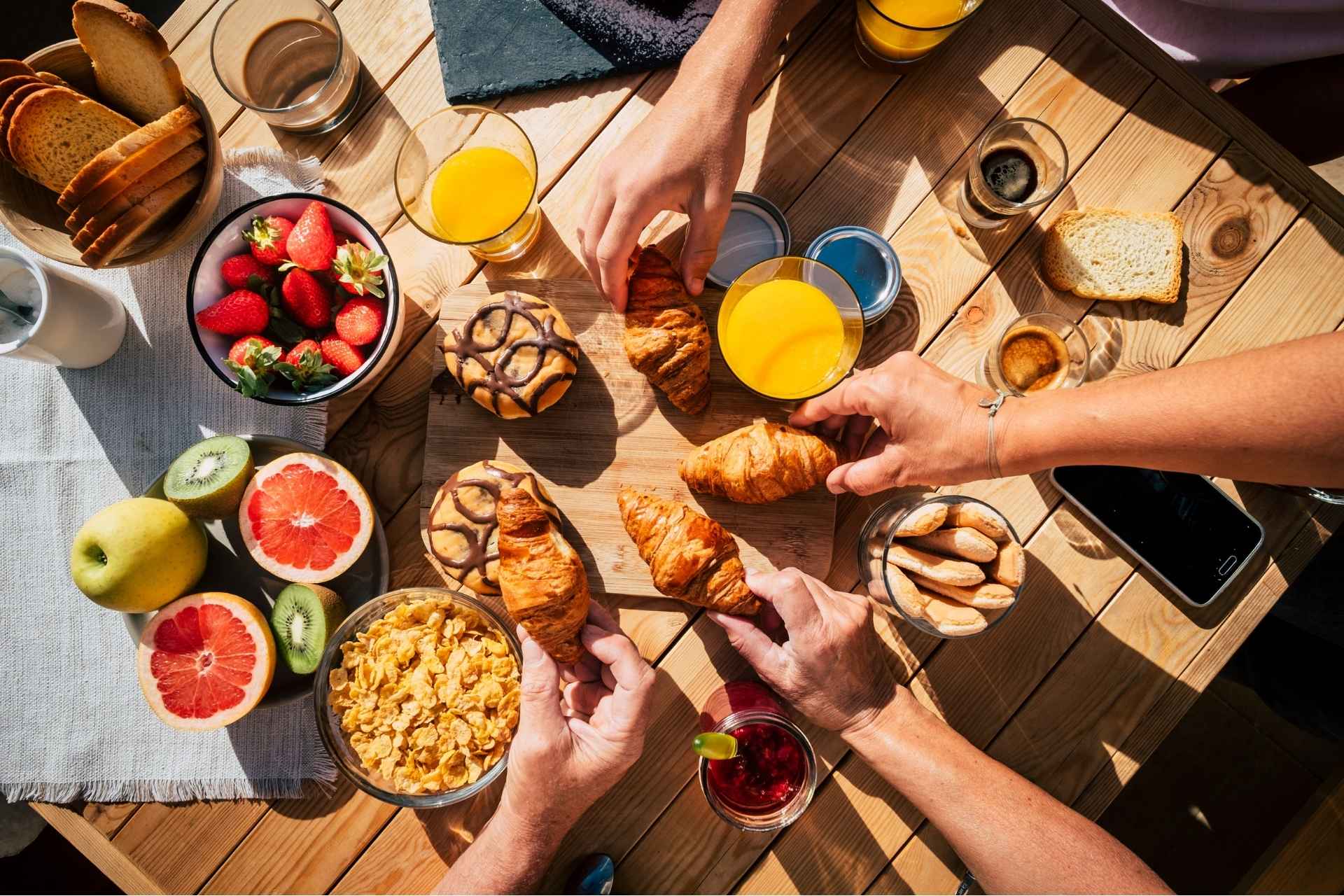 Vertical view of table full of breakfast food and group of people eating and enjoying it
